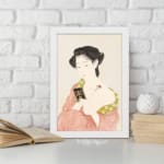Vintage Japanese wall art featuring a woman in traditional dress holding a book with soft red and green patterns. displayed on the wall in a white frame