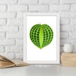 Heart-shaped green leaf with light and dark green patterns on a white background, framed in white, vintage botanical wall art displayed on the wall