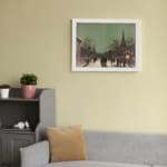 Infidu vintage wall art featuring a winter city scene with snowy streets, people walking, horse-drawn carriages, and warm golden lights from historic buildings, creating a cozy, old-fashioned atmosphere. displayed on the wall art in a white frame