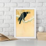 Infidu vintage wall art featuring a black crow perched on a snow-covered tree against a soft beige or light golden background, creating a timeless and artistic winter scene. displayed on the wall art in a white frame