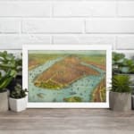 Vintage aerial view of a historic waterfront city with detailed buildings, boats, and earthy tones. displayed on the wall in a white frame