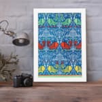 Vintage wall art with intricate decorative patterns in blue, red, green, and yellow, set against a blue background with a white frame. displayed on the wall