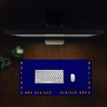 Infidu blue desk pad with “Believe and Achieve” quote in bold orange text on a deep blue background.