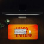 Infidu desk pad with bold red "Learn From Failure" quote on an orange to red gradient background.