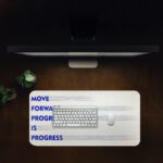 Infidu minimal cream desk pad with blue motivational quote "MOVE FORWARD PROGRESS IS PROGRESS" and subtle gray brush accents