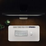 Infidu beige desk pad with motivational quote "HARD TIMES PASS STAY STRONG" and bold purple accent on a clean white background