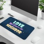 Infidu navy desk pad with “Love Your Neighbor” Bible verse in colorful vintage lettering on a textured blue background.
