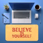 Infidu desk pad with bold red Believe in Yourself text on a soft yellow background and subtle vintage texture.