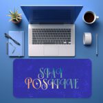 Infidu royal blue desk pad with “Stay Positive” quote in colorful pastel font and marble texture background.