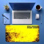 Infidu bold yellow desk pad with black grunge edges and motivational quote “STOP THINKING START DOING” in a vintage art style.