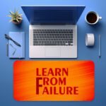Infidu desk pad with bold red "Learn From Failure" quote on an orange to red gradient background.