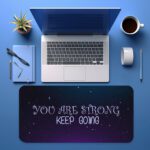 Infidu galaxy desk pad with “YOU ARE STRONG KEEP GOING” quote on a blue to purple starry background.