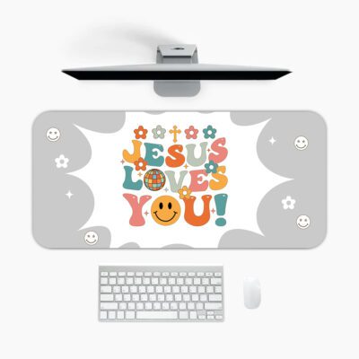 Light gray desk pad with “Jesus Loves You!” colorful text, surrounded by crosses, stars, hearts, smiley faces, and a happy emoji in vintage art style.