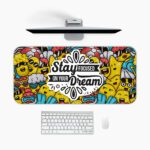 Colorful doodle-style desk pad with cartoon characters and “Stay Focused On Your Dream” quote in black text on a white cloud-like shape.