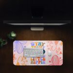 Groovy desk pad with “Stay Trippy Little Hippie” quote, bold floral background, cartoon mustache, and sunglasses in vintage art style.