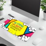 Colorful comic-style desk pad with bold triangular shapes, cartoon clouds, and “Be Strong and Courageous” Bible verse in vintage art style.