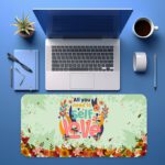 Infidu desk pad with “All You Need Is Self Love” quote, pastel green background, and colorful floral vintage art design.