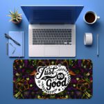 Dark floral desk pad with kaleidoscope pattern in purple, green, and orange, featuring “Just Do Good” quote in white framed text, vintage art style.