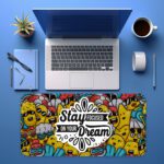Colorful doodle-style desk pad with cartoon characters and “Stay Focused On Your Dream” quote in black text on a white cloud-like shape.