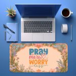 Desk pad with pastel floral border and colorful “Pray More, Worry Less” quote on a warm cream background in vintage art style.